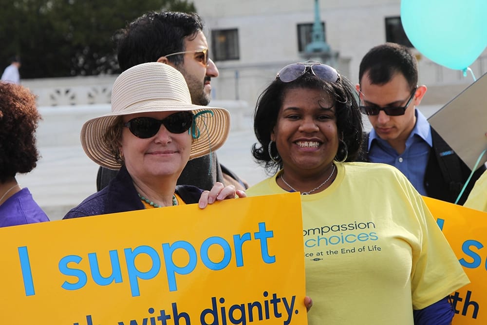 Supporters hold signs and wear Compassion and Choices shirts in front of the Supreme Court Building