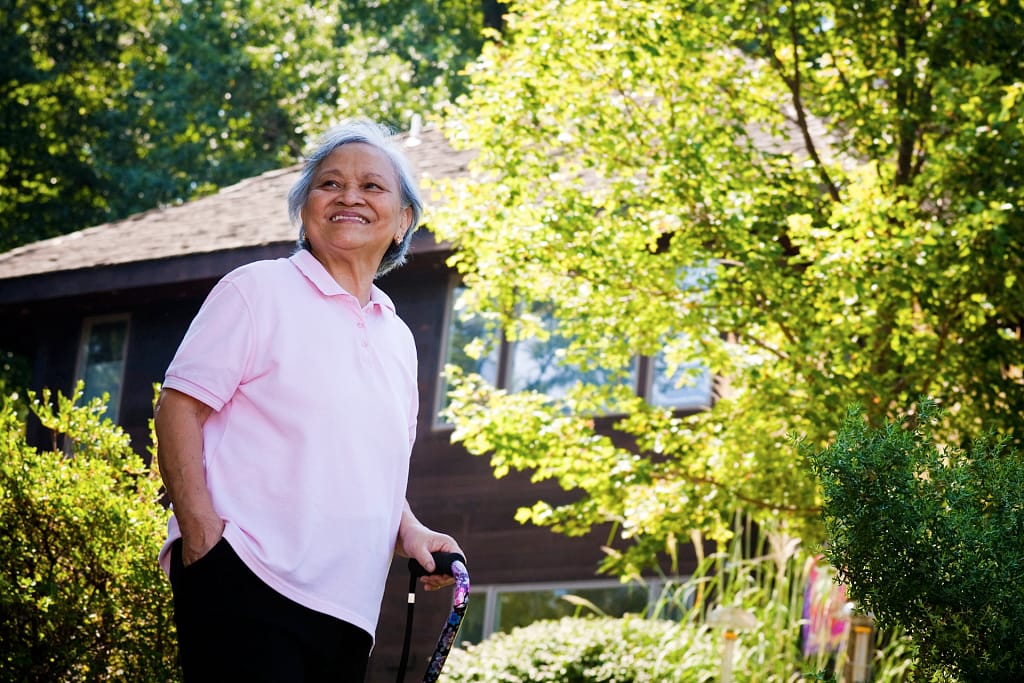 Asian woman with cane walking in the back yard