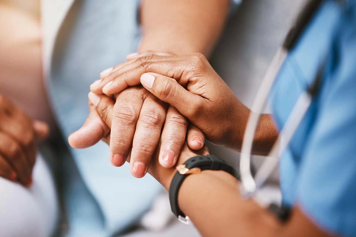 A close up of a doctor holding the hand of a paitent
