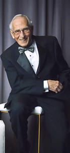 Ted Rubenstein wearing a tuxedo sitting on a table