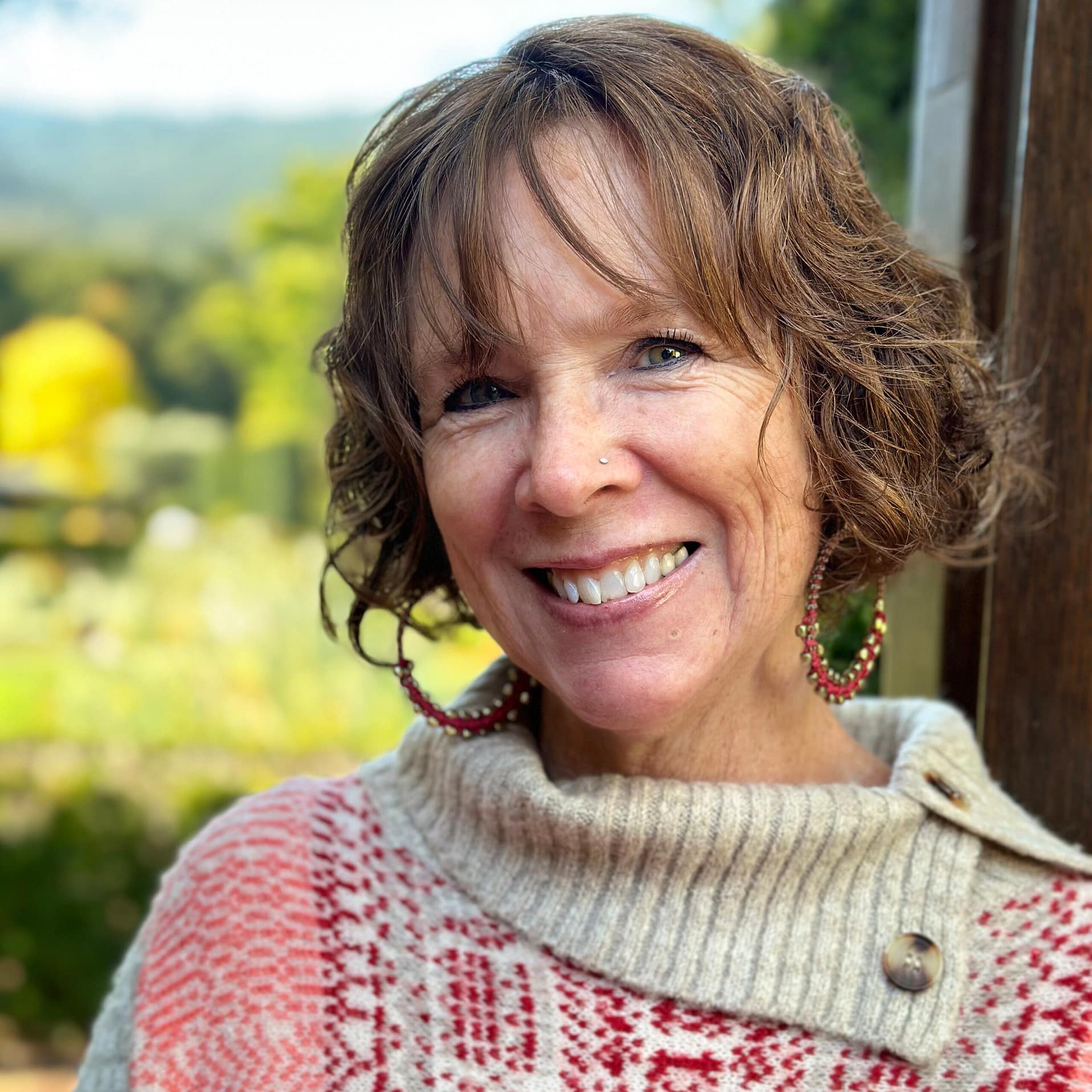 Gabby Jimenez smiling standing in front of a window with scenic background.