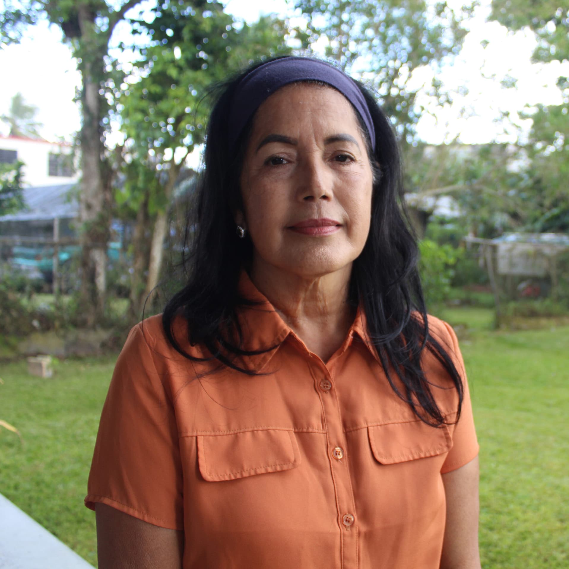 Nilsa Centeno standing in her back yard wearing an orange shirt