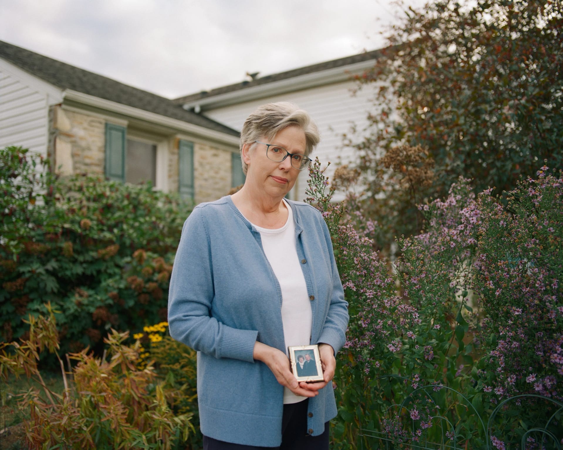 barbara mancini pictured outside holding a photo of her parents.