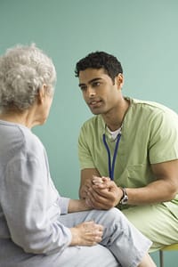 Doctor in green scrubs speaking with a senior patient