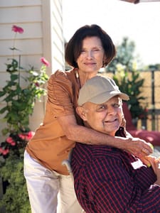 Elaine and Joe Pereia pose together embrasing outside a house