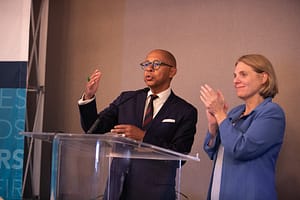 Dr. Jeff Gardere and Compassion & Choices Pres./CEO Kim Callinan stand at a podium clapping