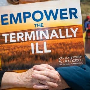 Woman holding Empower the Terminally Ill Sign