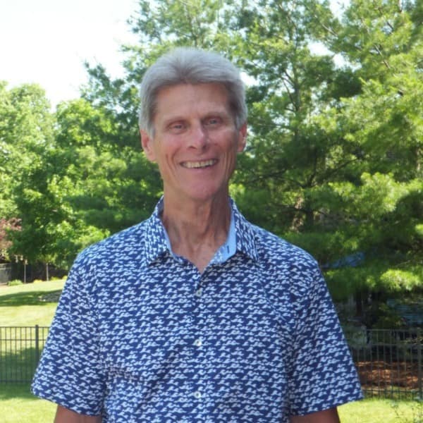 Tom Bretz stands outside wearing a blue shirt