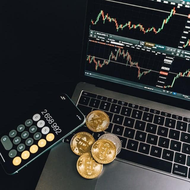 crypto currency on a laptop with a calculator app open on an iphone