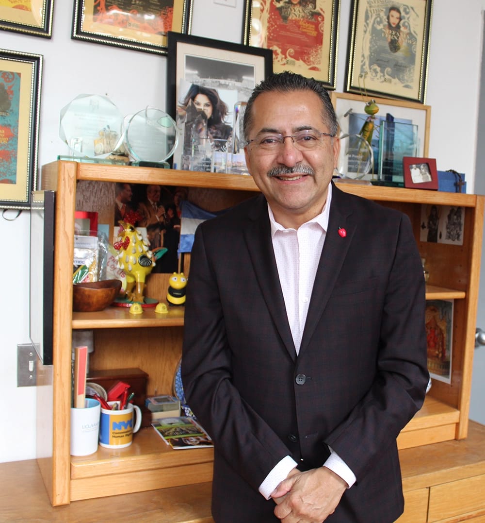 Guillermo Chacon standing in front of a bookshelf smiling