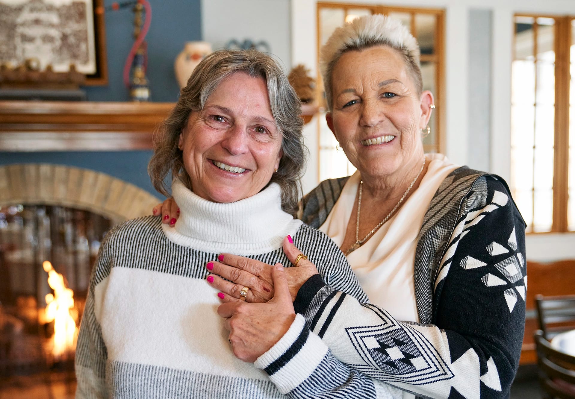 Two women smiling in front of a fireplace